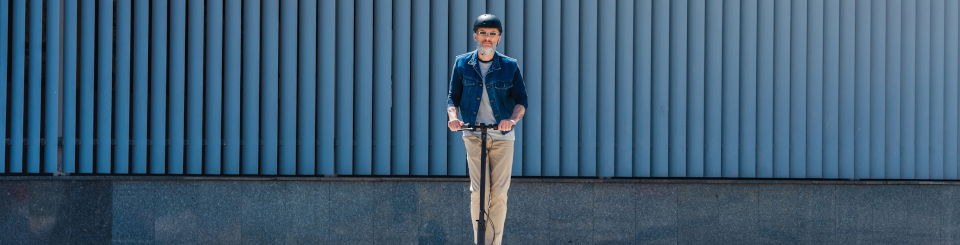 Hombre con casco y gafas de sol montado sobre un patinete eléctrico