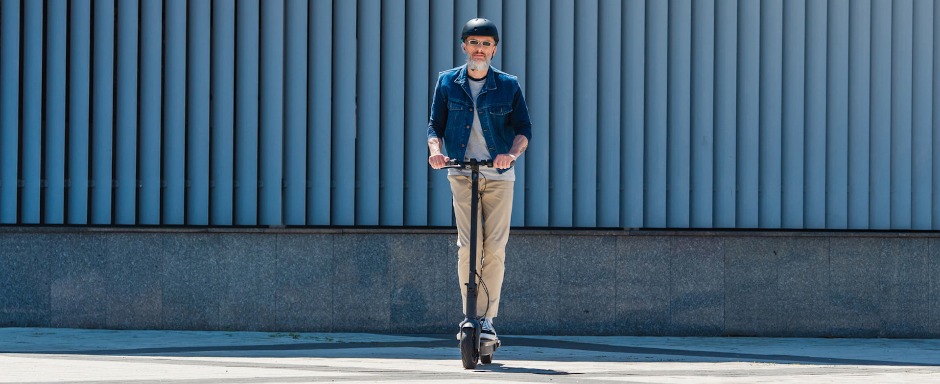 Hombre con casco y gafas de sol montado sobre un patinete eléctrico