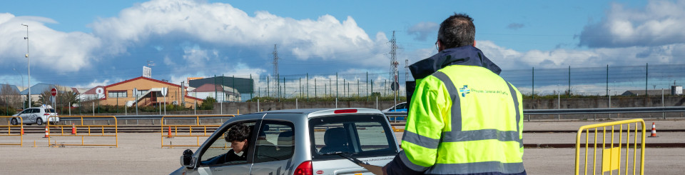 Examinador observando como un conductor está aparcando un coche de autoescuela en un parking