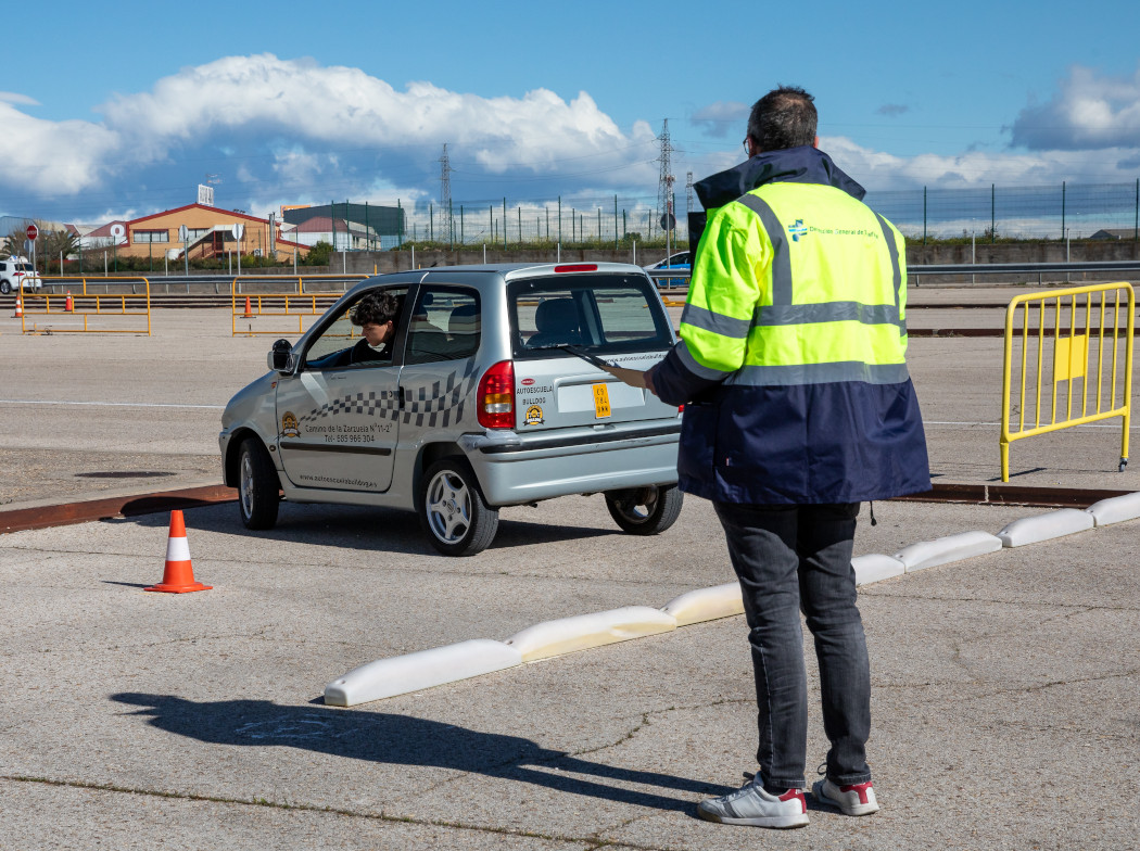 Examinador observando como un conductor está aparcando un coche de autoescuela en un parking
