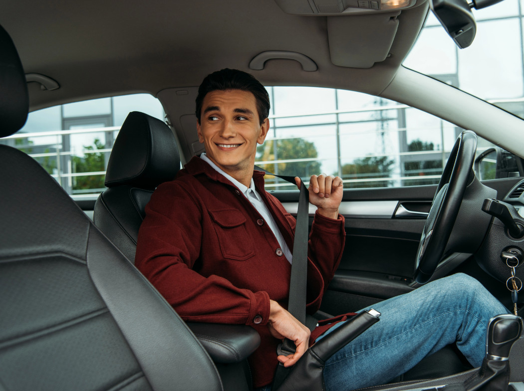 Hombre sentado en el interior de un coche abrochándose el cinturón de seguridad