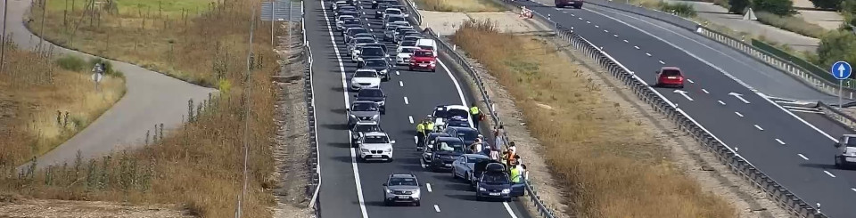 Autopista con vehículos circulando y un vehículo accidentado en el carril de la derecha.