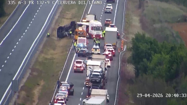 Imagen de un accidente en una autopista donde se ve un coche volcado en el arcén y varios coches y camiones parados.
