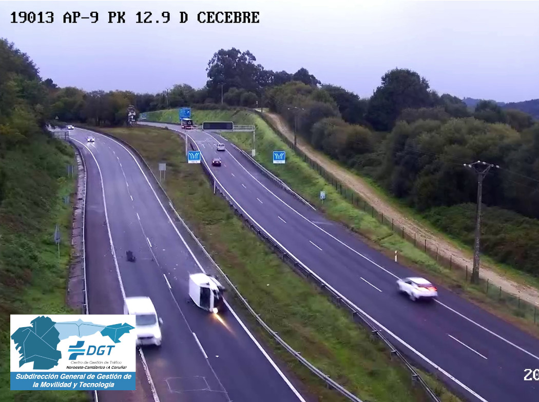 Autovía de dos carriles con coches circulando y una furgoneta volcada que bloquea uno de ellos