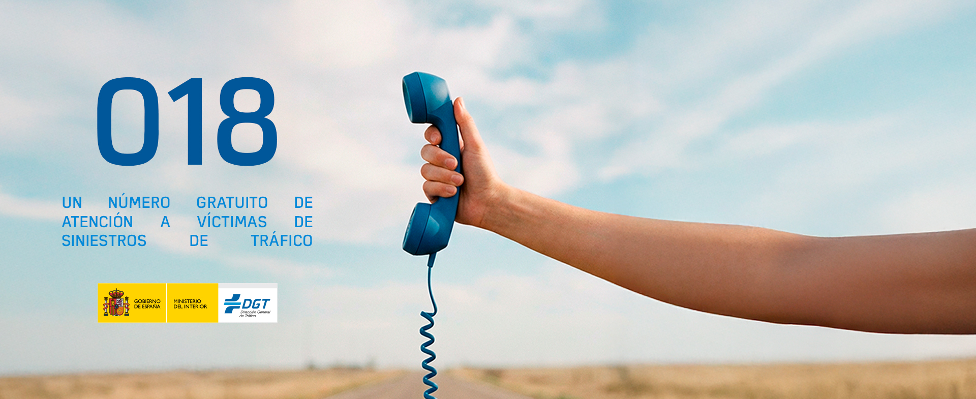 Imagen de una mano agarrando el auricular de un teléfono antiguo. A su lado se puede leer "018, un número gratuito de atención a víctimas de siniestros de tráfico". Como fondo de imagen hay una carretera de campo.