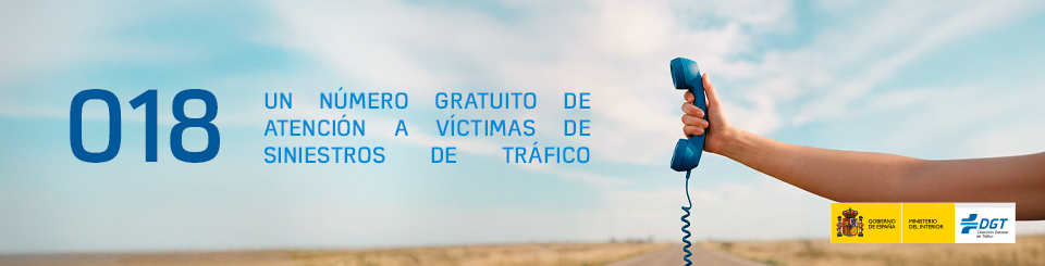Imagen de una mano agarrando el auricular de un teléfono antiguo. A su lado se puede leer "018, un número gratuito de atención a víctimas de siniestros de tráfico". Como fondo de imagen hay una carretera de campo.