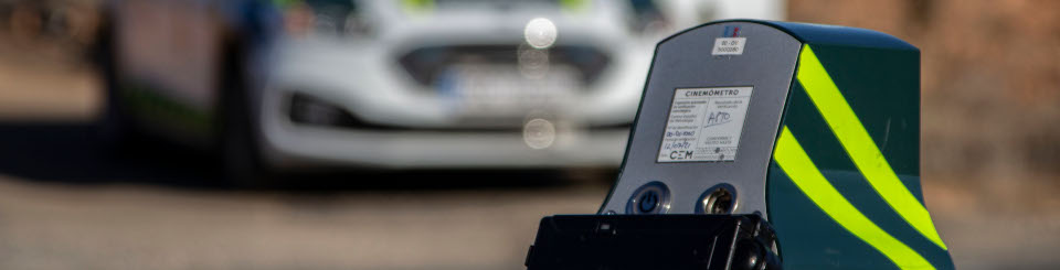 Veloláser en primer plano con un coche de la Guardia Civil desenfocado al fondo