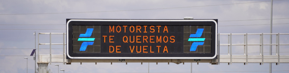 Fotografía de un cartel luminoso de carretera en el que se puede leer Motorista te queremos de vuelta.
