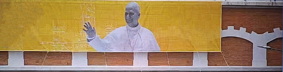 Cartel grande con la imagen del Papa León XIV desplegado en un puente de ladrillos.