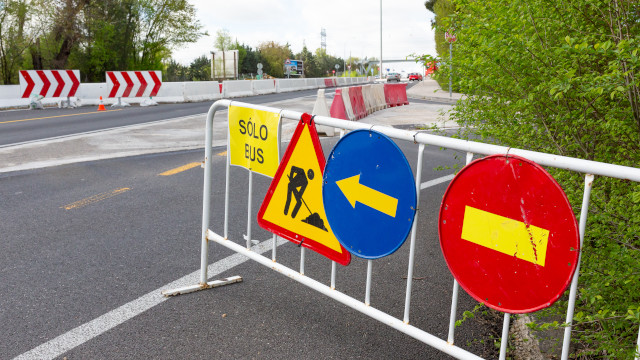 Vaya metálica en una autopista con diferentes señales de tráfico de obras colgadas