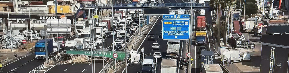 Autovía de Alicante de varios carriles transitada por vehículos. Entre dos de las vías hay un camión siniestrado en horizontal ocupando varios carriles.