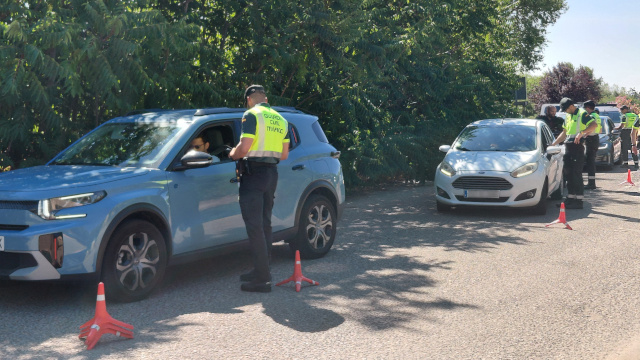 Un grupo de guardias civiles realiza un control de alcohol y drogas a los conductores de varios coches detenidos en una carretera, junto a una arboleda