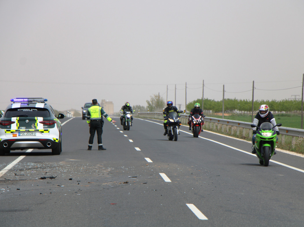 Carretera con motociclistas circulando y vigilada por una patrulla de la Guardia Civil