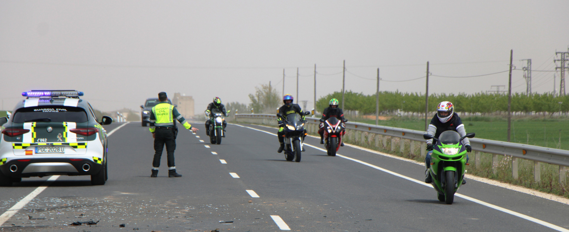 Carretera con motociclistas circulando y vigilada por una patrulla de la Guardia Civil