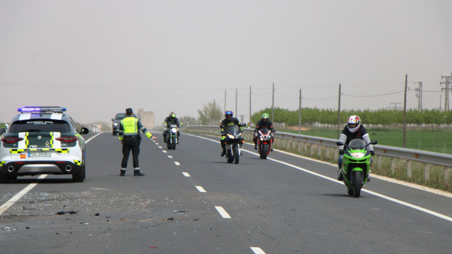 Carretera con motociclistas circulando y vigilada por una patrulla de la Guardia Civil 