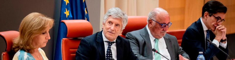 El ministro del Interior, el director de Tráfico y otras dos personas, sentados tras una mesa y leyendo documentos en una reunión.