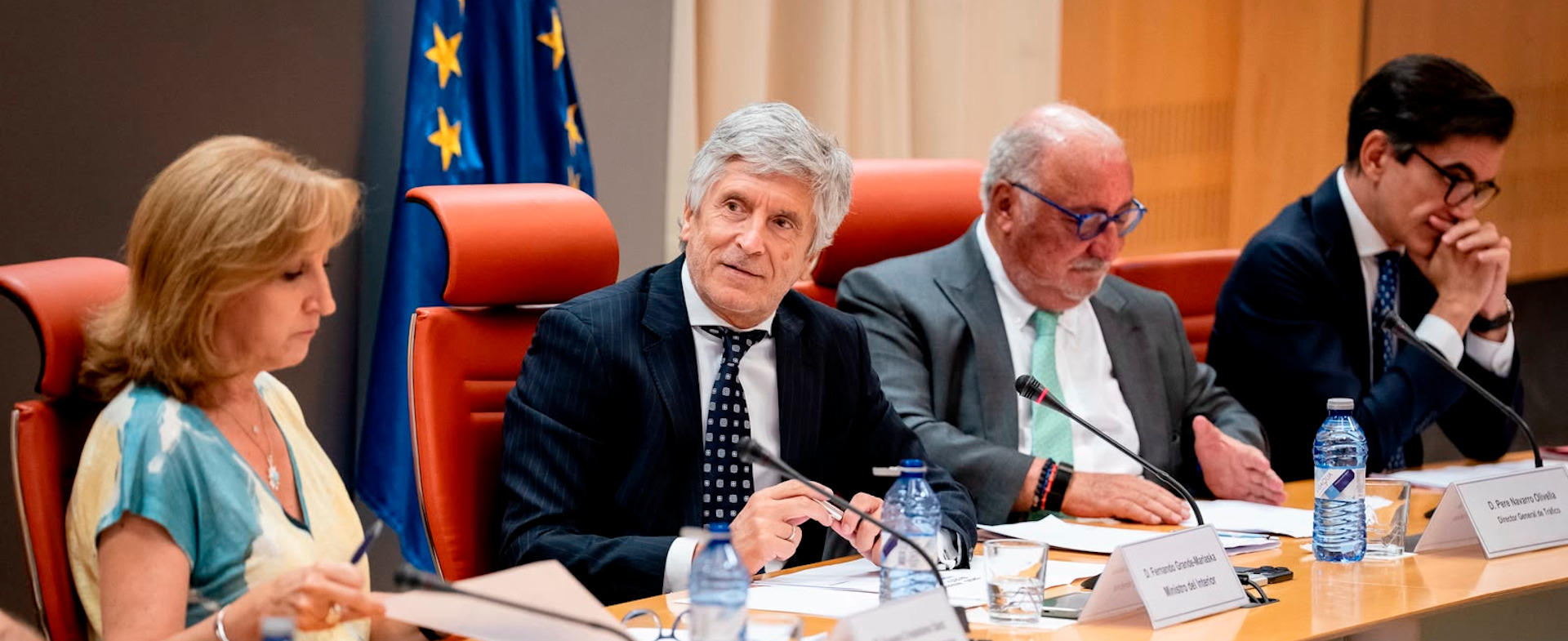 El ministro del Interior, el director de Tráfico y otras dos personas, sentados tras una mesa y leyendo documentos en una reunión.
