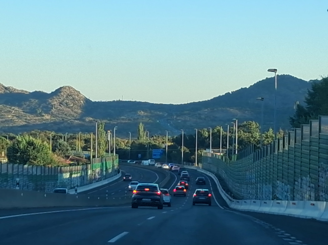 Autopista con vehículos circulando con montaña al fondo