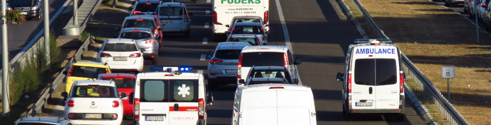 Autopista con coches atascados y ambulancia circulando por carril de la derecha