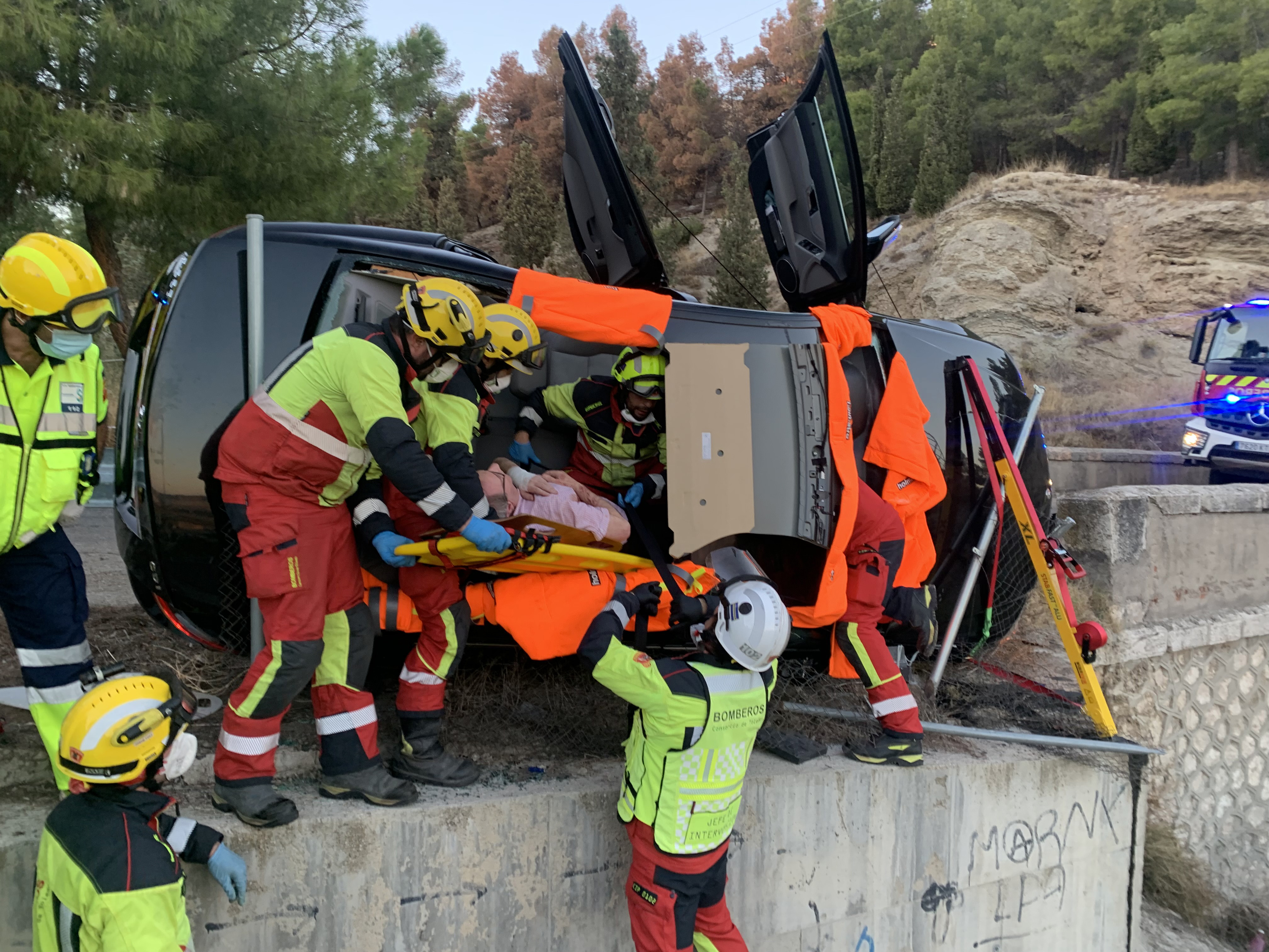Grupo de bomberos rescatando a un hombre de su vehículo accidentado