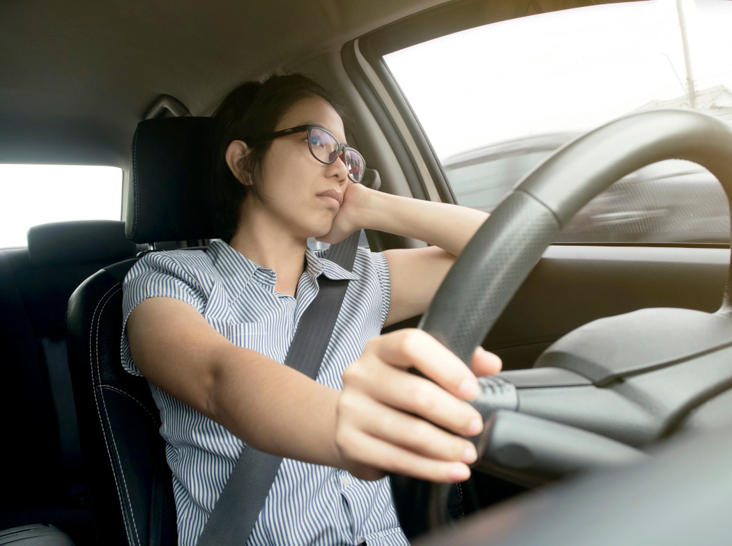 Mujer al volante con expresión de cansancio