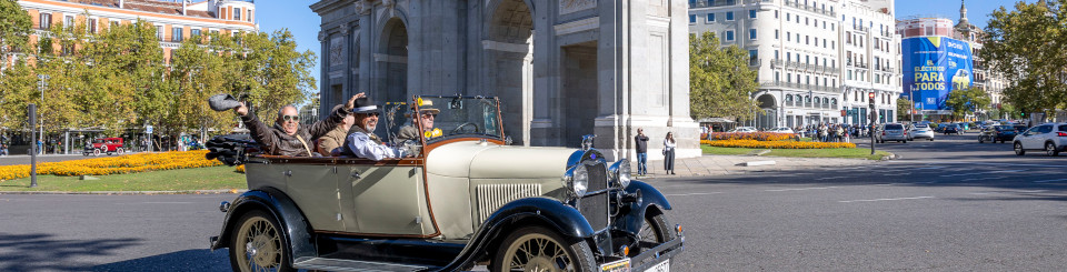 Tres hombres montados en un vehículo histórico descapotable en Madrid
