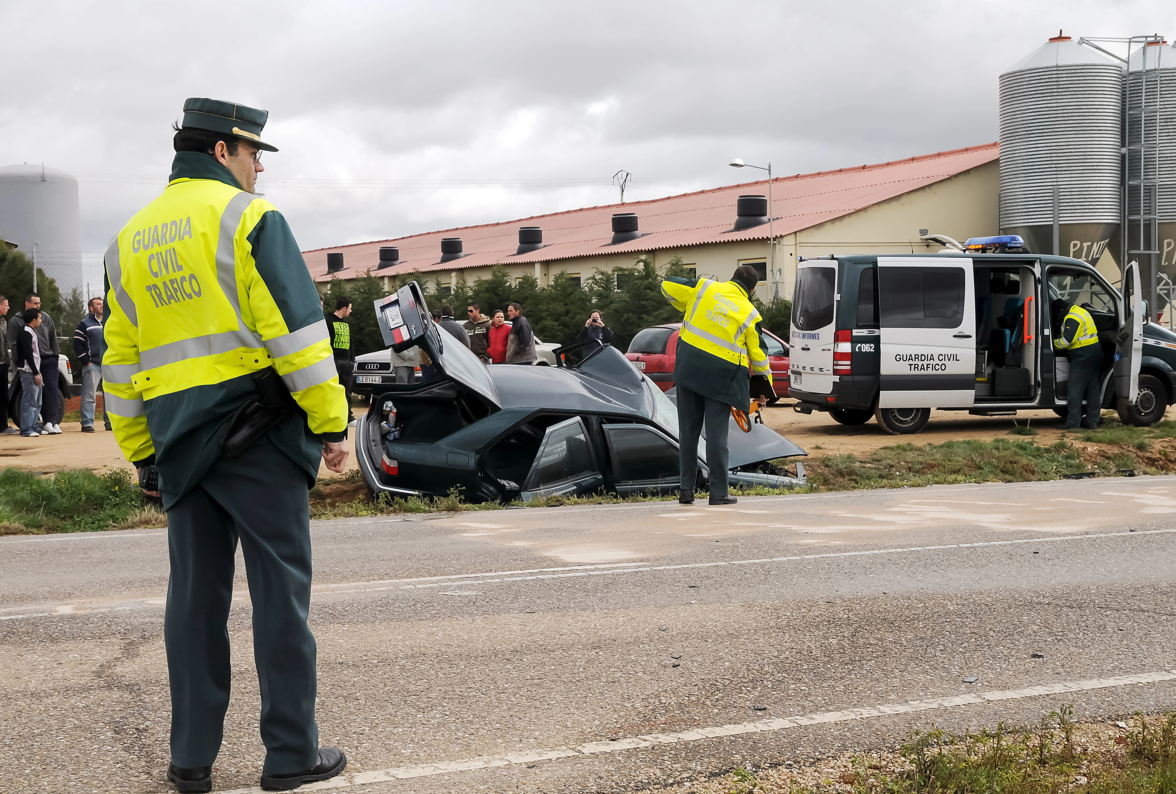 Guardia Civil atendiendo un accidente de un vehículo volcado en una carretera cerca de una fábrica