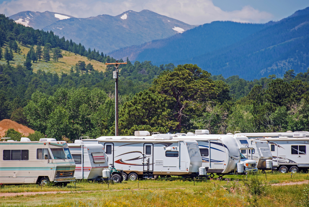 Varias caravanas estacionadas una junto a otra, con un paisaje montañoso y boscoso al fondo