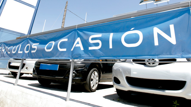 Cartel de vehículos ocasión con coches detrás de él