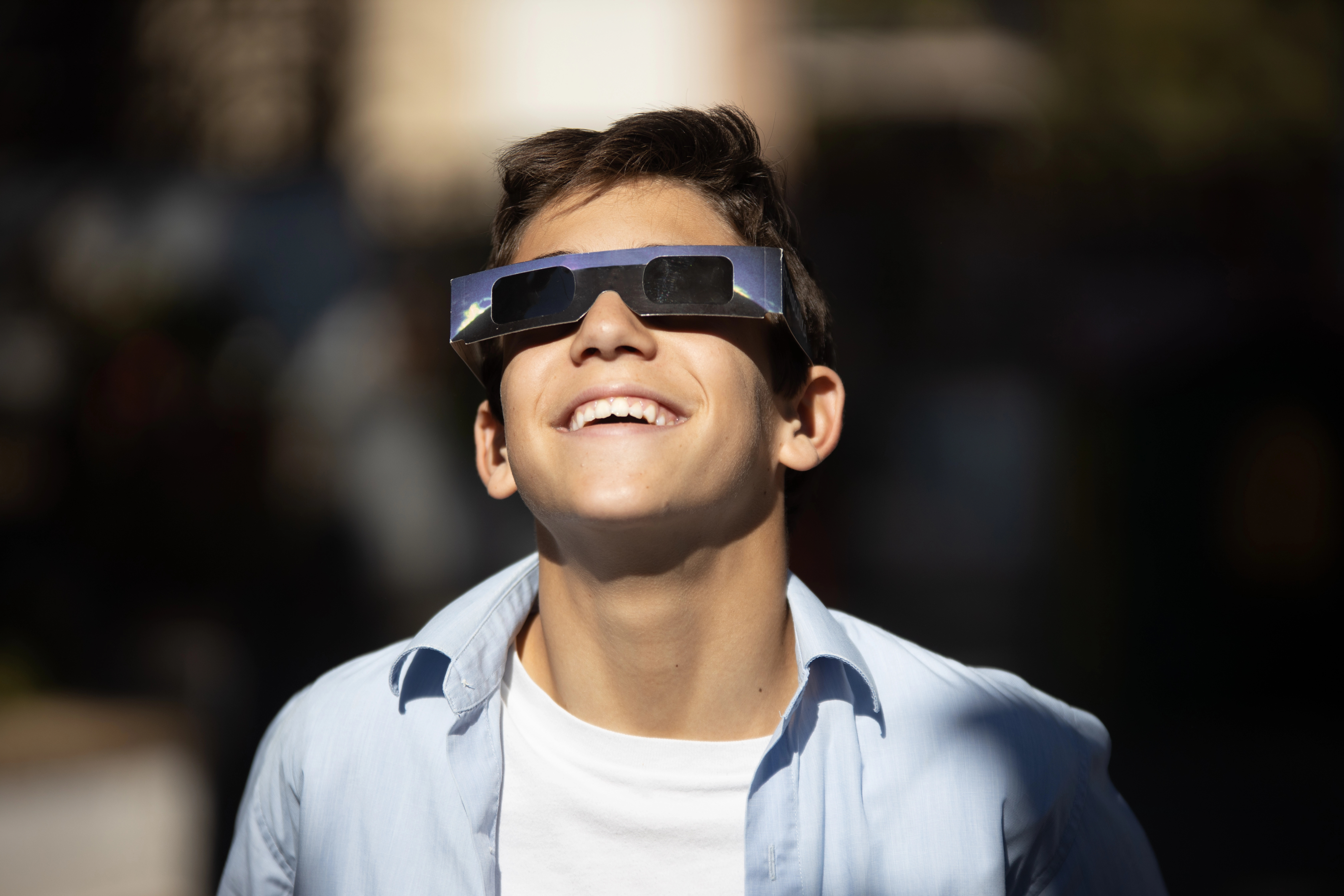 Niño con gafas de sol especiales para el eclipse mirando al cielo.