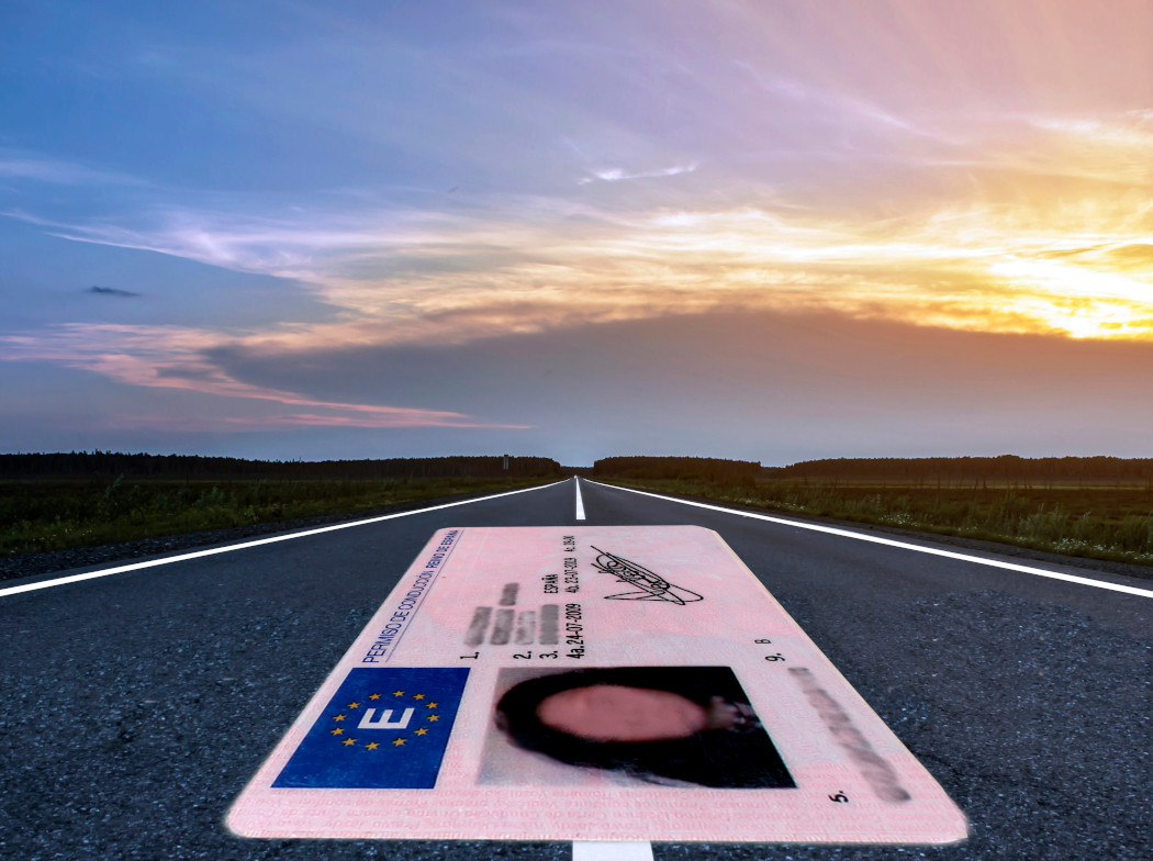 Carnet de conducir español de gran tamaño sobre una carretera al atardecer