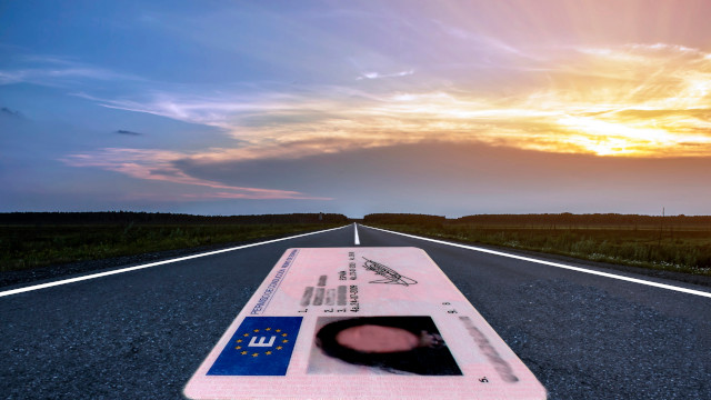 Carnet de conducir español de gran tamaño sobre una carretera al atardecer