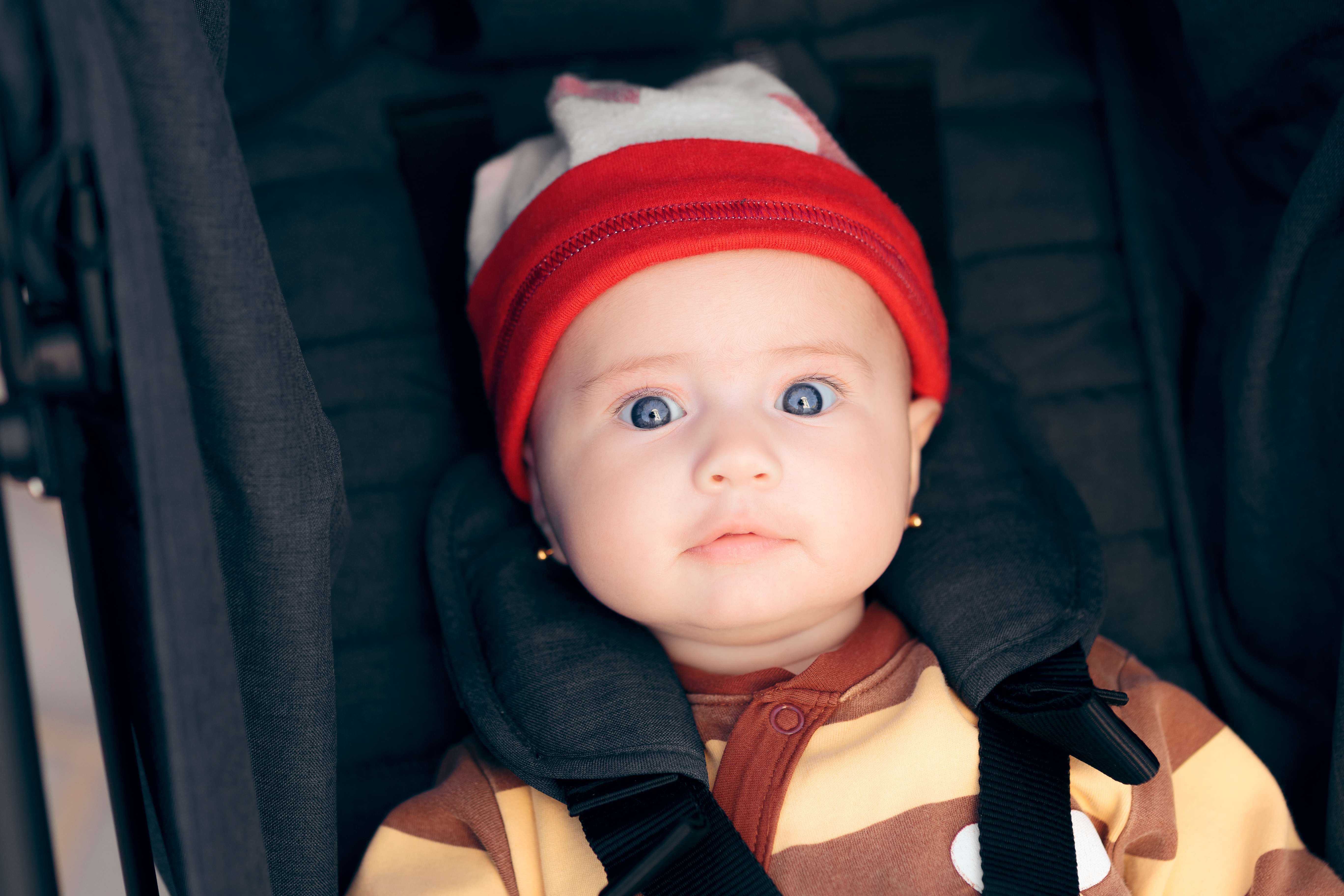 Niña de meses, que mira fijamente a la cámara mientras va en su sillita infantil en un coche