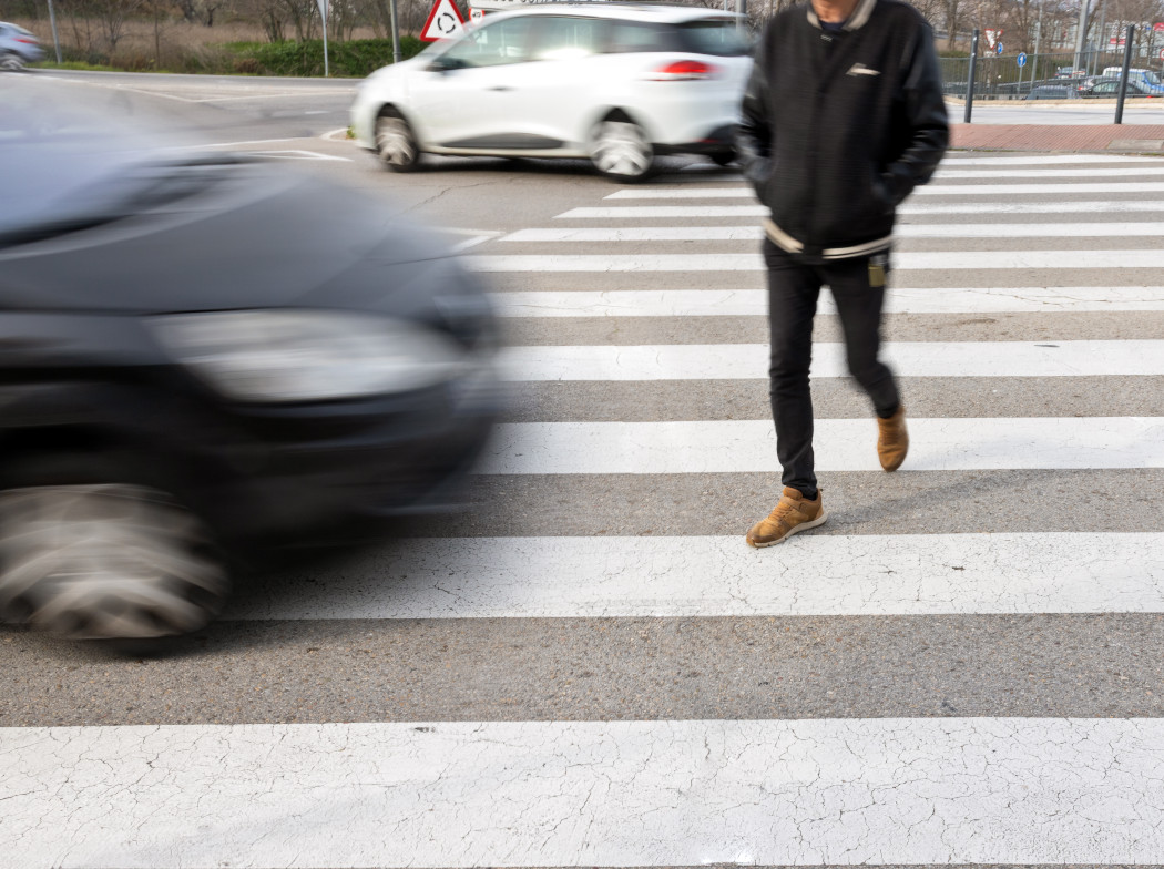 Vehículo rápido cerca de peatón cruzando en paso de cebra